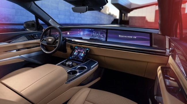 View of front seats, steering wheel and pillar-to-pillar screen in Cadillac ESCALADE IQ Sport.